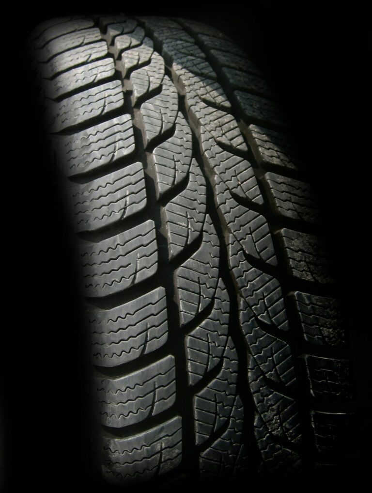 Close-up of a car tire tread with detailed grooves and patterns, highlighting the importance of proper tread depth and tires maintenance for road safety.