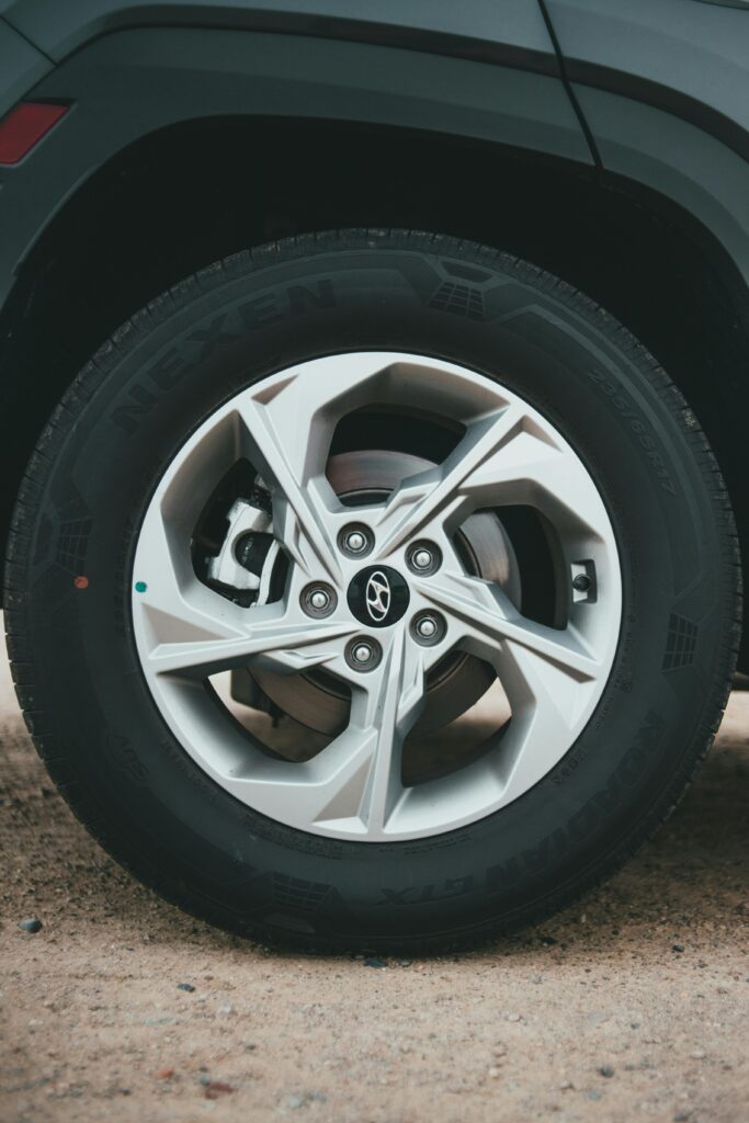 Close-up of a car wheel and tire, showcasing a well-maintained tire with clear tread and a sleek alloy rim, emphasizing the importance of tires upkeep for vehicle safety and performance.