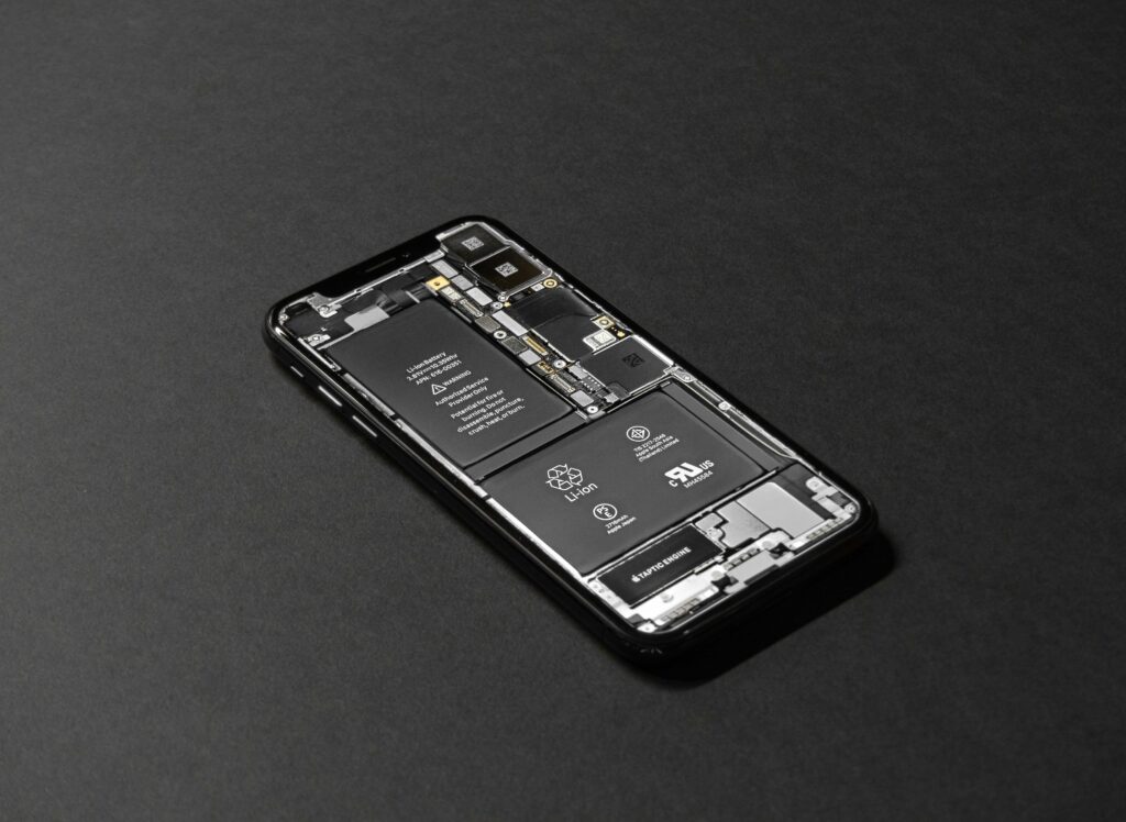 Close-up view of a smartphone with its back cover removed, revealing the internal lithium-ion battery and components, highlighting the importance of proper handling and storage to prevent battery fires.